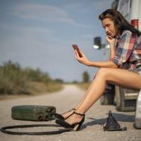 Девушка на проселочной дороге у заглохшей машины - телефон